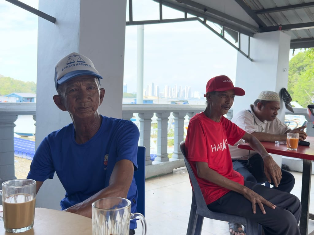 A Barisan Nasional supporter sits beside a Pakatan Harapan fan at a local shop in Kampung Sungai Melayu, Iskandar Puteri, on the eve of Johor’s state election in Malaysia. Photo: Iman Muttaqin Yusof A Barisan Nasional supporter sits beside a Pakatan Harapan fan at a local shop in Kampung Sungai Melayu, Iskandar Puteri, on the eve of Johor’s state election in Malaysia. Photo: Iman Muttaqin Yusof