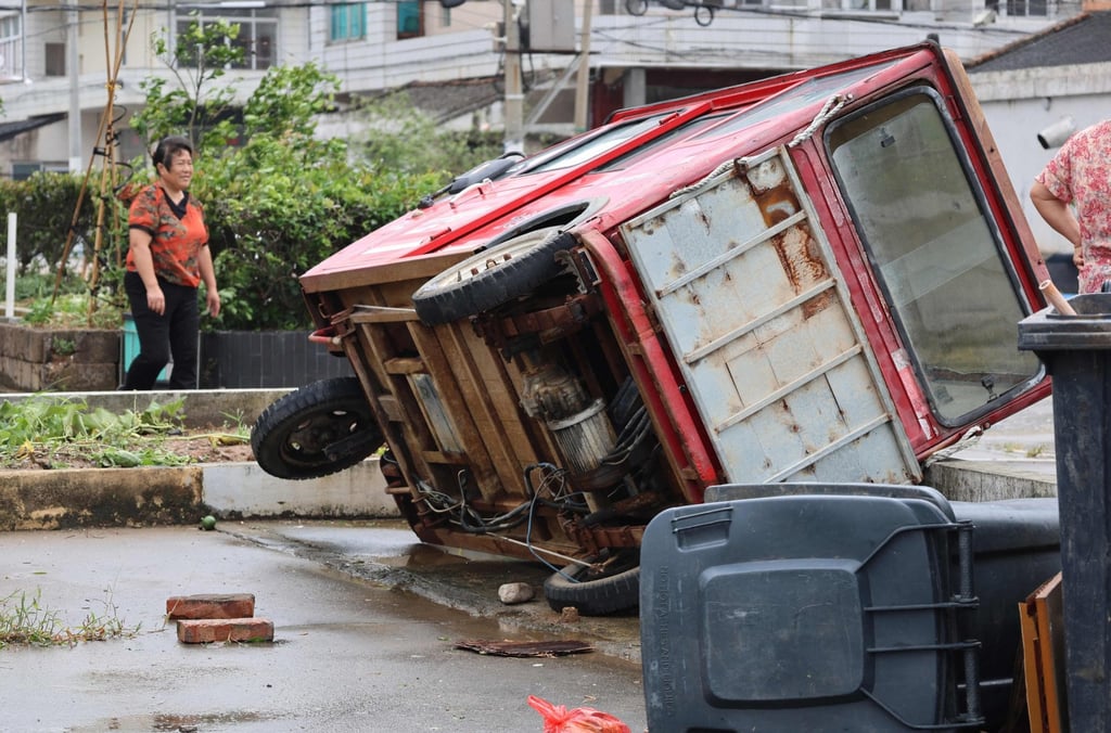 A woman walks past a vehicle knocked over by winds from Typhoon Bavi in Wenling, in China’s eastern Zhejiang province on July 12, 2026. Photo: AFP A woman walks past a vehicle knocked over by winds from Typhoon Bavi in Wenling, in China’s eastern Zhejiang province on July 12, 2026. Photo: AFP