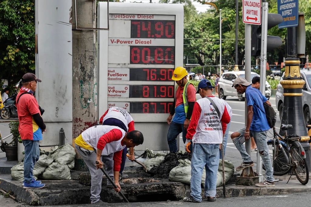 Workers declog a drainage canal beside a petrol station displaying fuel prices in Manila, the Philippines, on Monday. Photo: EPA Workers declog a drainage canal beside a petrol station displaying fuel prices in Manila, the Philippines, on Monday. Photo: EPA
