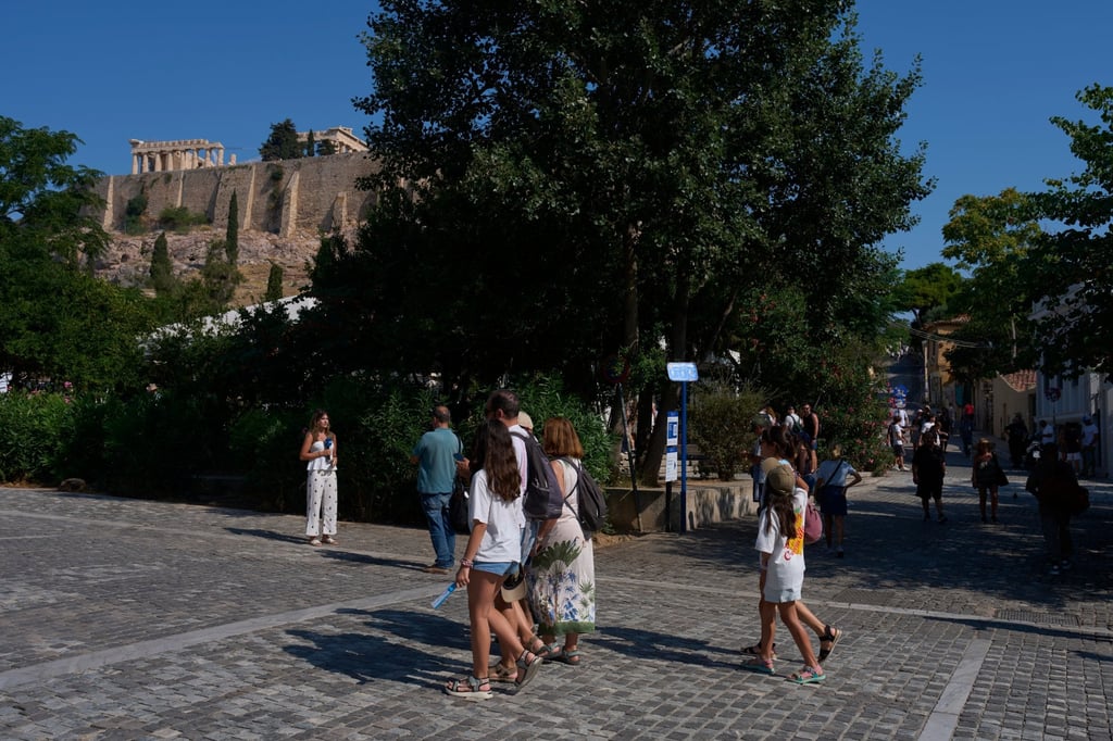 Tourists walk near the Acropolis in Athens on Tuesday after two tourists were stabbed and injured nearby in an attack near the entrance to the archaeological site. Photo: AP Tourists walk near the Acropolis in Athens on Tuesday after two tourists were stabbed and injured nearby in an attack near the entrance to the archaeological site. Photo: AP