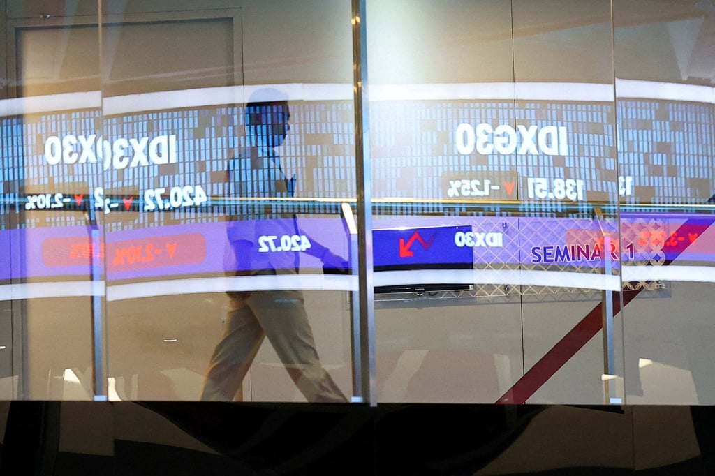 A man walks past a glass window reflecting an electronic sign showing the stock market index at the Indonesia Stock Exchange in Jakarta. Photo: Reuters A man walks past a glass window reflecting an electronic sign showing the stock market index at the Indonesia Stock Exchange in Jakarta. Photo: Reuters