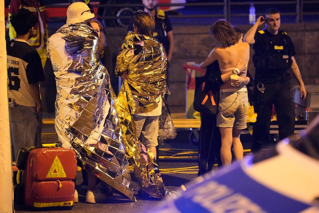 Two people embrace near others wearing thermal blankets in Berlin early on Sunday. Photo: AP Two people embrace near others wearing thermal blankets in Berlin early on Sunday. Photo: AP