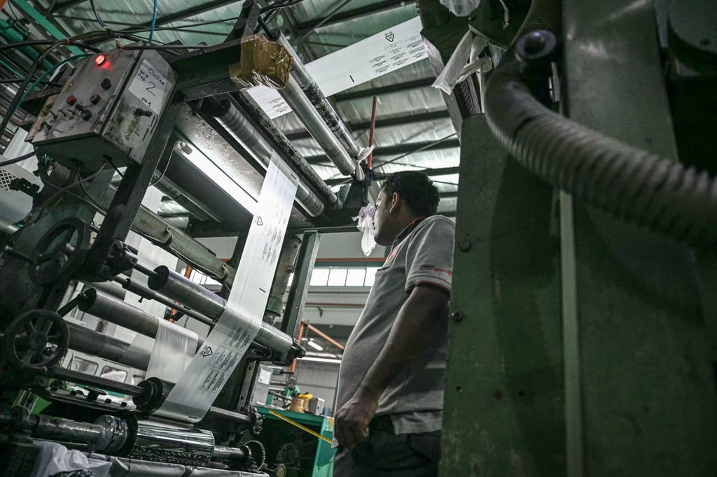A worker inspects a machine processing high-density plastic products at a factory in Klang, Malaysia, on October 9, 2024. Photo: AFP A worker inspects a machine processing high-density plastic products at a factory in Klang, Malaysia, on October 9, 2024. Photo: AFP
