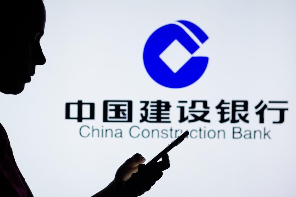 In this photo illustration, a woman’s silhouette holds a smartphone with the China Construction Bank Corporation logo in the background. Photo: Shutterstock Images
