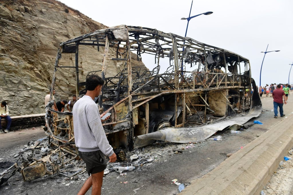 People stand near a burned-out bus at the site of clashes at a border crossing near Fnideq, Morocco, on Friday. Photo: EPA People stand near a burned-out bus at the site of clashes at a border crossing near Fnideq, Morocco, on Friday. Photo: EPA