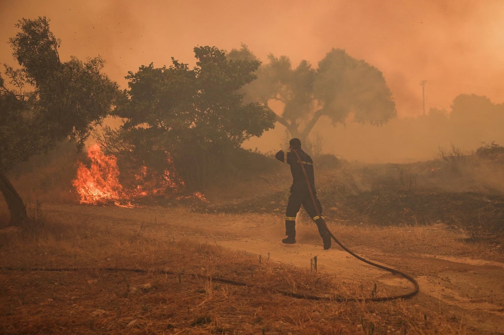 A fireman runs to extinguish a fire in an olive grove in the settlement of Zachouli, Greece, on Sunday. Photo: Reuters A fireman runs to extinguish a fire in an olive grove in the settlement of Zachouli, Greece, on Sunday. Photo: Reuters