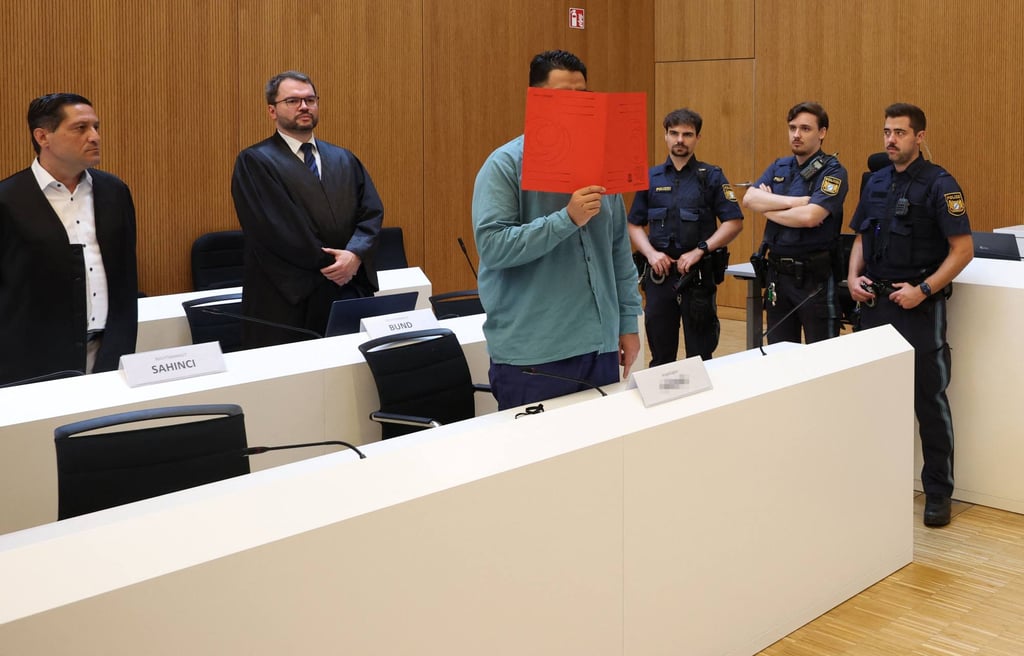 Farhad N. (third from left) covers his face with a folder as he stands in the dock at the Higher Regional Court in Munich on Thursday. Photo: AFP