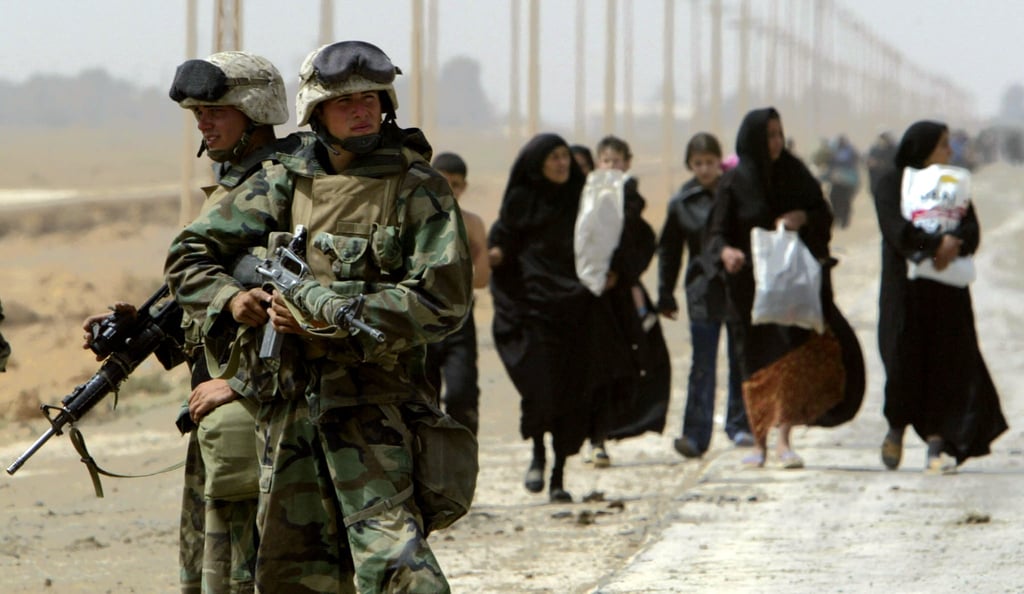 Iraqi women, refugees from Baghdad, walk next to US Marines in the Iraqi capital in 2003. Photo: Reuters Iraqi women, refugees from Baghdad, walk next to US Marines in the Iraqi capital in 2003. Photo: Reuters