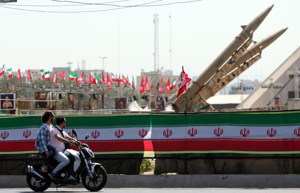 Motorcyclists drive past Iranian missiles on display above a banner depicting US President Trump at Azadi Square in Tehran on July 30. Photo: EPA Motorcyclists drive past Iranian missiles on display above a banner depicting US President Trump at Azadi Square in Tehran on July 30. Photo: EPA