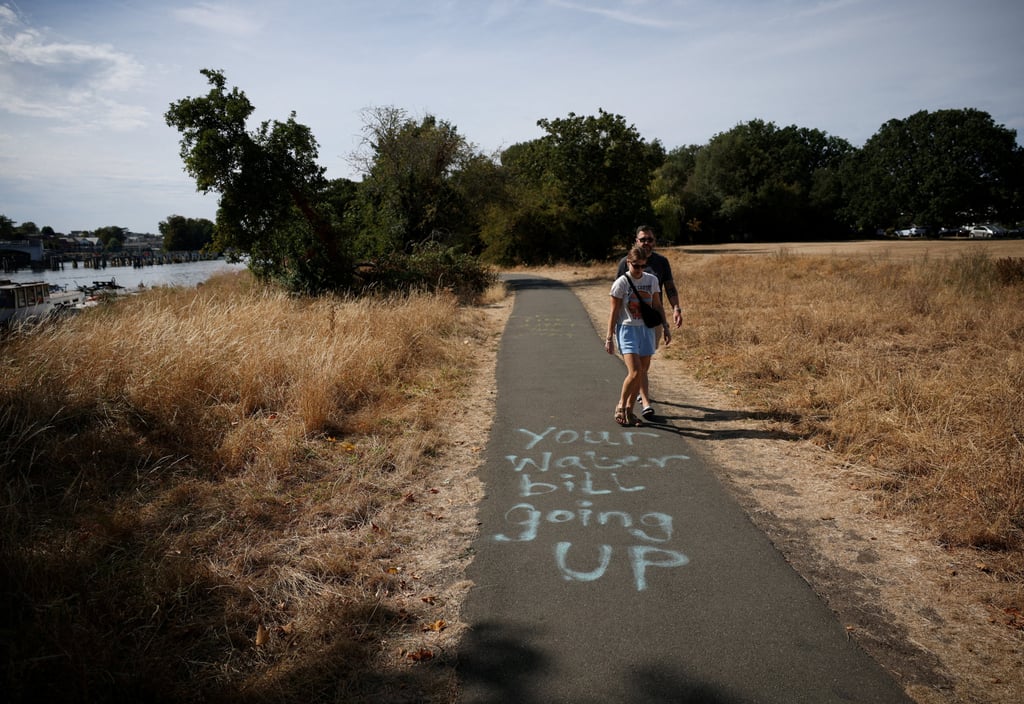 A couple a few miles from London walk past a spray-painted message opposing Thames Water. Photo: Reuters A couple a few miles from London walk past a spray-painted message opposing Thames Water. Photo: Reuters