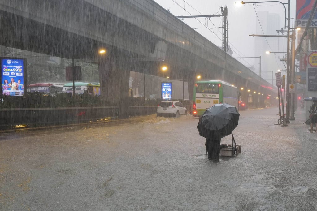 People walk in a flooded street after heavy rains hit Manila on Monday. Photo: dpa
