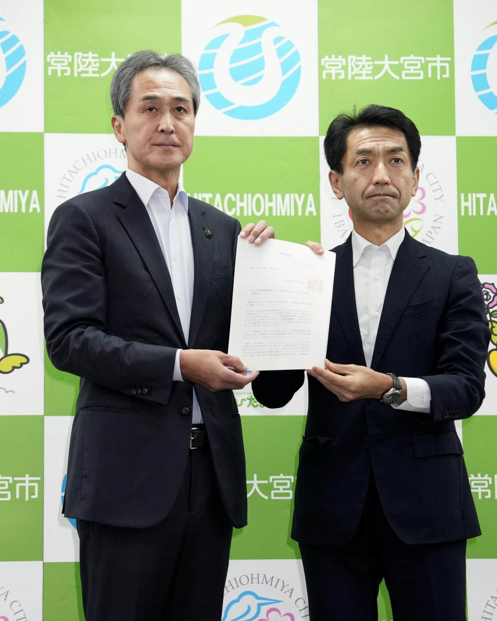 Hitachiomiya Mayor Sadayuki Suzuki (left) receives a written request to conduct a preliminary survey for selecting his city as a potential disposal site for highly radioactive waste on Monday. Photo: Kyodo