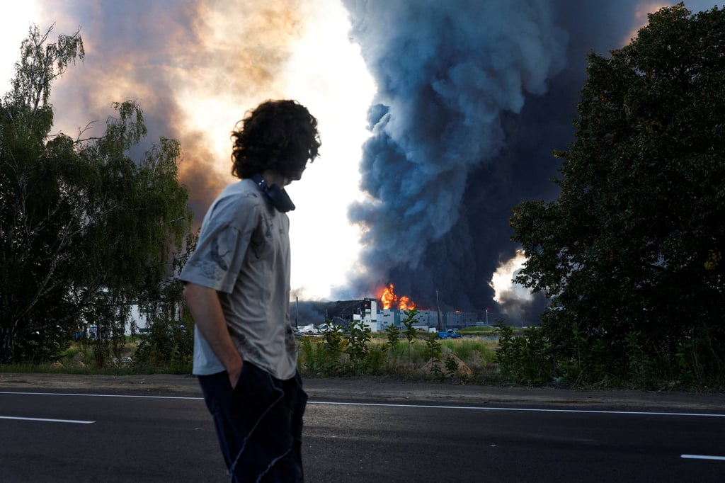 A man looks on as smoke rises over a warehouse in the Kyiv region hit by a Russian drone strike on August 27. Photo: Reuters