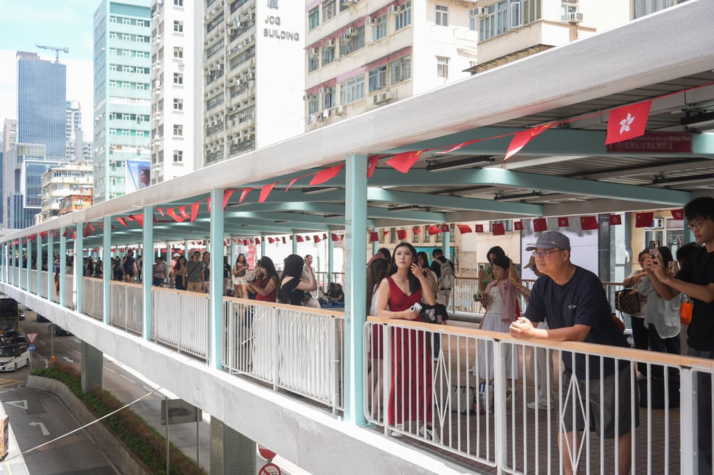 Tourists take pictures from a footbridge in Mong Kok. Photo: Eugene Lee Tourists take pictures from a footbridge in Mong Kok. Photo: Eugene Lee