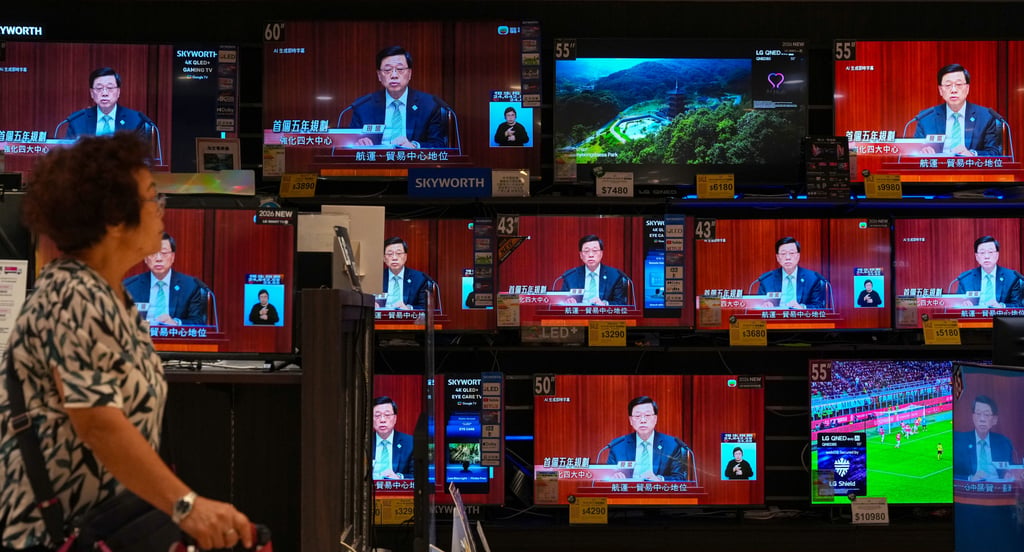 A woman walks past a live broadcast of Chief Executive John Lee delivering the five-year plan and policy address. Photo: Karma Lo A woman walks past a live broadcast of Chief Executive John Lee delivering the five-year plan and policy address. Photo: Karma Lo