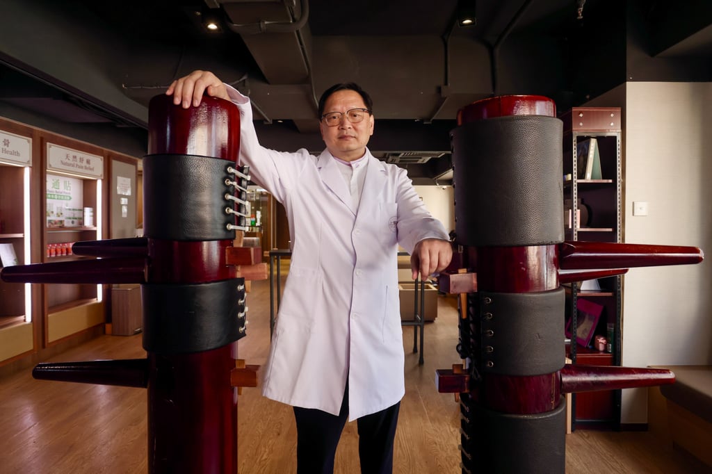 Yung stands between traditional wing chun wooden dummies (muk yan jong) at his clinic, highlighting the long-standing link between TCM and martial arts conditioning. Photo: Jonathan Wong