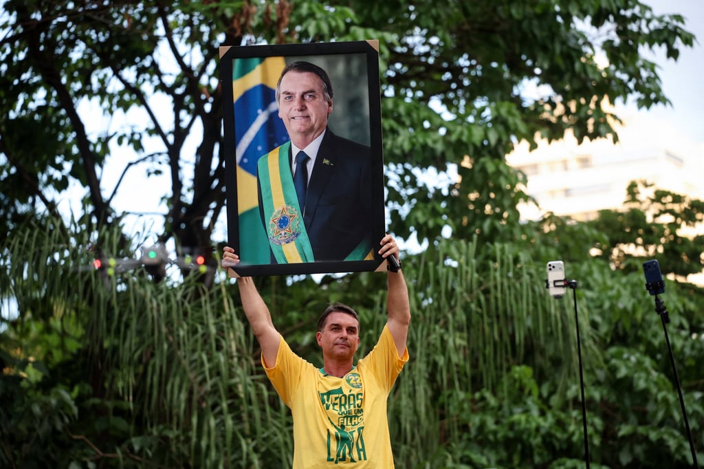 Brazilian presidential candidate Flavio Bolsonaro holds up a portrait of his father, Brazil’s former president Jair Bolsonaro, during a campaign rally in Goiania. Photo: Reuters