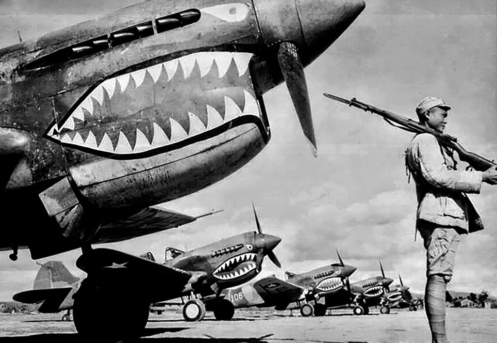 A Chinese soldier guards a line of American fighter planes, painted with the shark-mouth nose art of the Flying Tigers, parked at an airbase in mainland China in 1941 or 1942. Photo: Handout