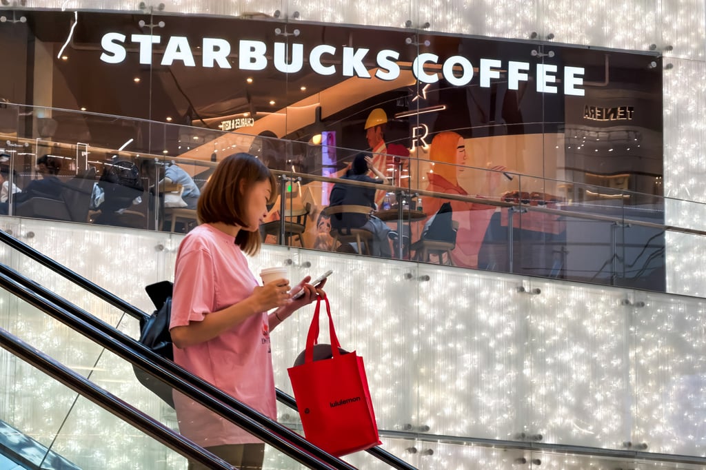 A woman uses a smartphone while riding an escalator near a Starbucks store in Shenzhen, China, on March 23, 2026. Photo: Getty Images A woman uses a smartphone while riding an escalator near a Starbucks store in Shenzhen, China, on March 23, 2026. Photo: Getty Images