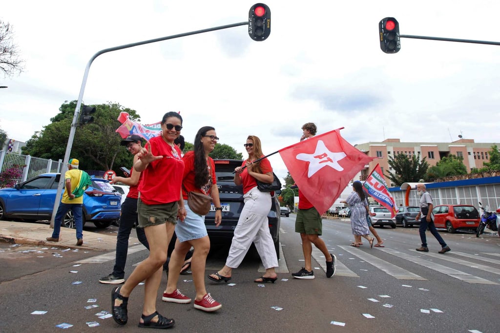 Supporters of Lula cross a street carrying campaign flags during the presidential election in Brasilia, Brazil on Sunday. Photo: AFP Supporters of Lula cross a street carrying campaign flags during the presidential election in Brasilia, Brazil on Sunday. Photo: AFP