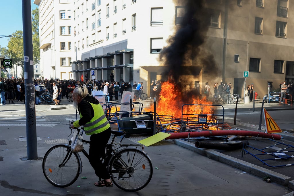 A person rides a bicycle past burning fire during a French high school and university students’ demonstration in Lyon on Tuesday. Photo: Reuters A person rides a bicycle past burning fire during a French high school and university students’ demonstration in Lyon on Tuesday. Photo: Reuters