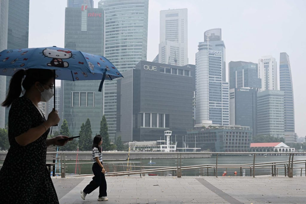 People walk along the boulevard at Marina Bay as buildings are seen shrouded with haze in Singapore on Tuesday. Photo: AFP