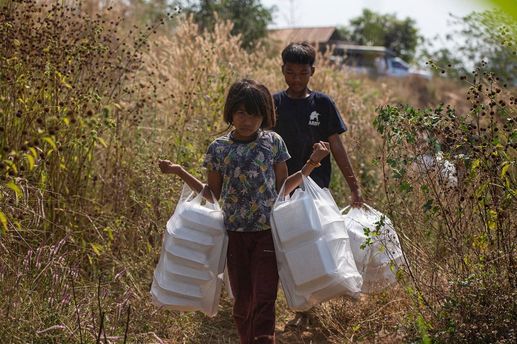 Young Myanmar refugees walk with food aid in Thailand’s Mae Sot district in 2022, after fleeing military clashes with armed opposition groups. Photo: AFP