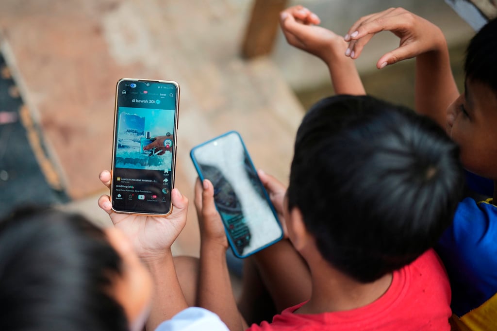 Boys use their mobile phones in Jakarta in April. Indonesia’s child protection regulations have already had an effect on how social media companies operate. Photo: AP Boys use their mobile phones in Jakarta in April. Indonesia’s child protection regulations have already had an effect on how social media companies operate. Photo: AP