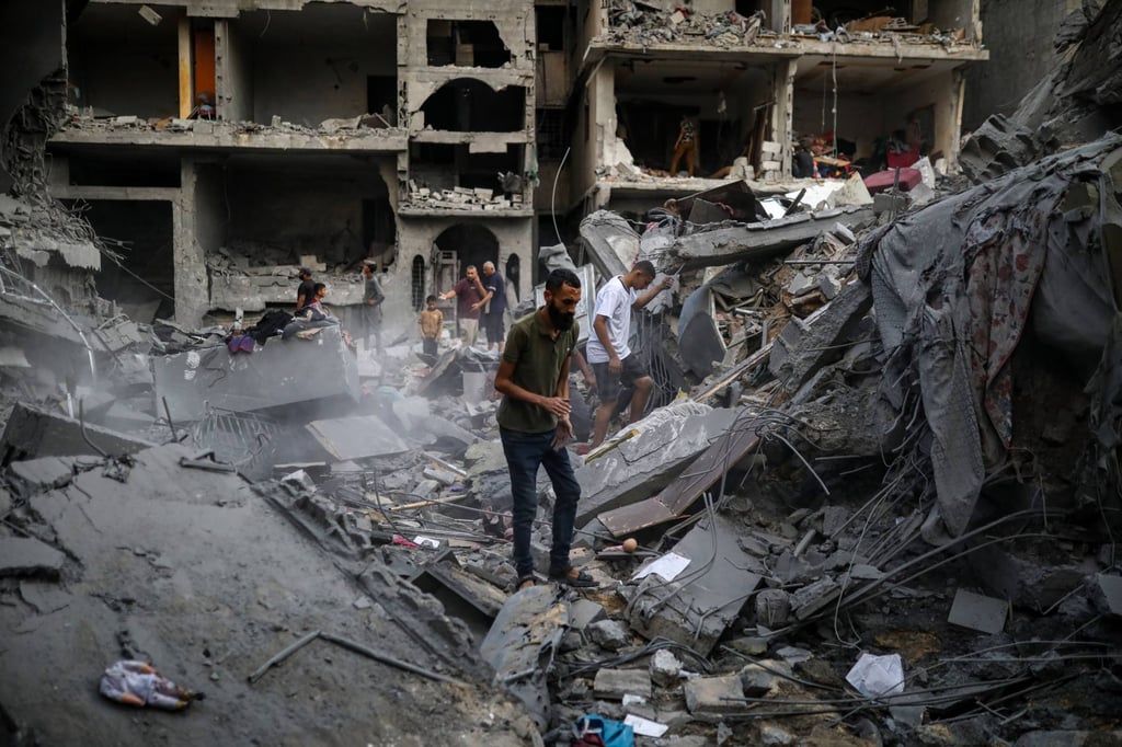 Palestinians inspect their belongings amid the rubble of damaged residential buildings following an Israeli air strike south of Gaza City. Photo: Bilal Osama/APA Images via ZUMA