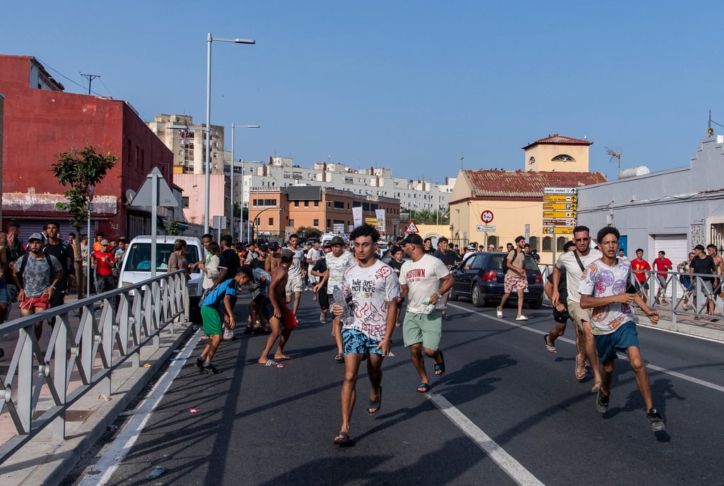 Migrants run from police officers after crossing from Morocco into the Spanish enclave of Ceuta, in July. Photo: AP