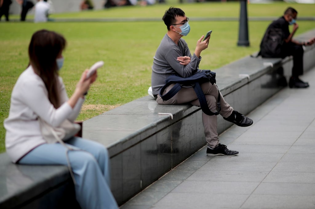 Office workers use their phones in the financial district of Singapore. The city state’s Internet Code of Practice requires licensed providers to comply with rules on prohibited material. Photo: EPA-EFE