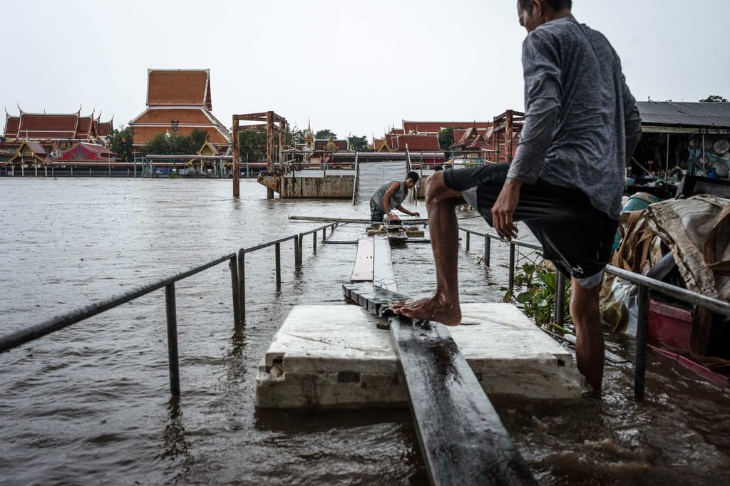 Residents use wooden planks and foam to build a makeshift bridge over floodwaters opposite Wat Phanan Choeng Worawihan temple in Ayutthaya province on October 6. Photo: AFP