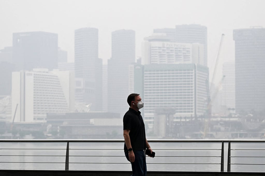 A pedestrian wearing a mask walks along the boulevard at Marina Bay as buildings are seen shrouded with haze in Singapore on Monday. Photo: AFP A pedestrian wearing a mask walks along the boulevard at Marina Bay as buildings are seen shrouded with haze in Singapore on Monday. Photo: AFP