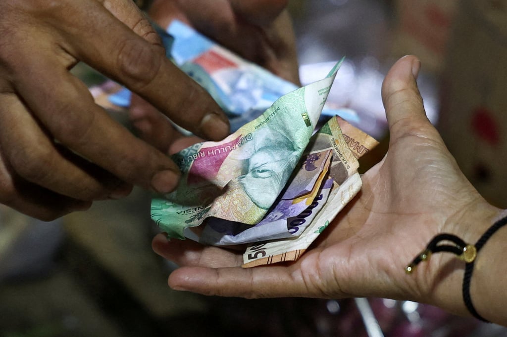 A vendor and customer exchange Indonesian rupiah banknotes. Photo: Reuters A vendor and customer exchange Indonesian rupiah banknotes. Photo: Reuters