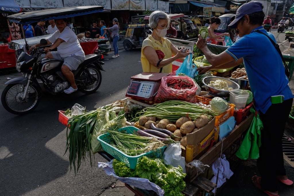 A vendor (right) engages with a customer (centre) at a market in Manila, the Philippines, on October 6. Photo: EPA