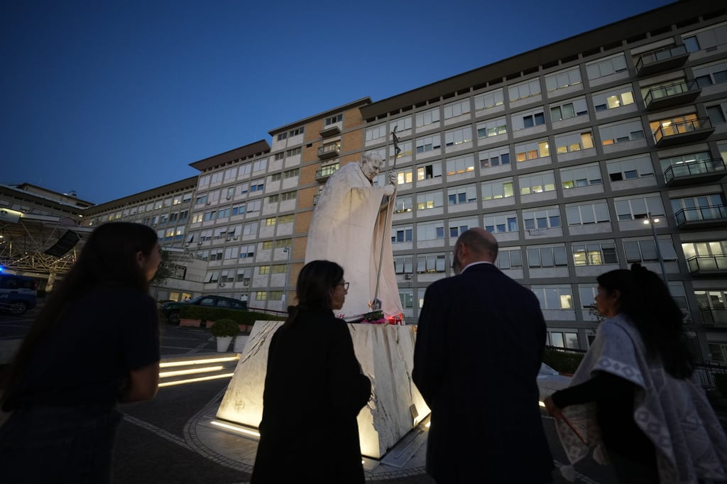 People gather to pray for Pope Leo next to a statue of John Paul II at the Agostino Gemelli Polyclinic in Rome on Friday. Photo: AP
