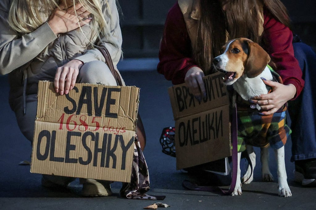 A dog looks on while women hold posters at a rally in Kyiv on October 6 demanding the establishment of a humanitarian corridor to evacuate Ukrainian civilians from the town of Oleshky. Photo: Reuters