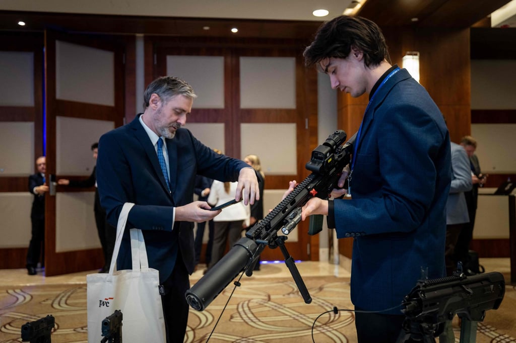 Participants inspect a weapon displayed at a stand during the second day of Warsaw Security Forum in Warsaw, Poland, on Tuesday 13. Photo: AFP