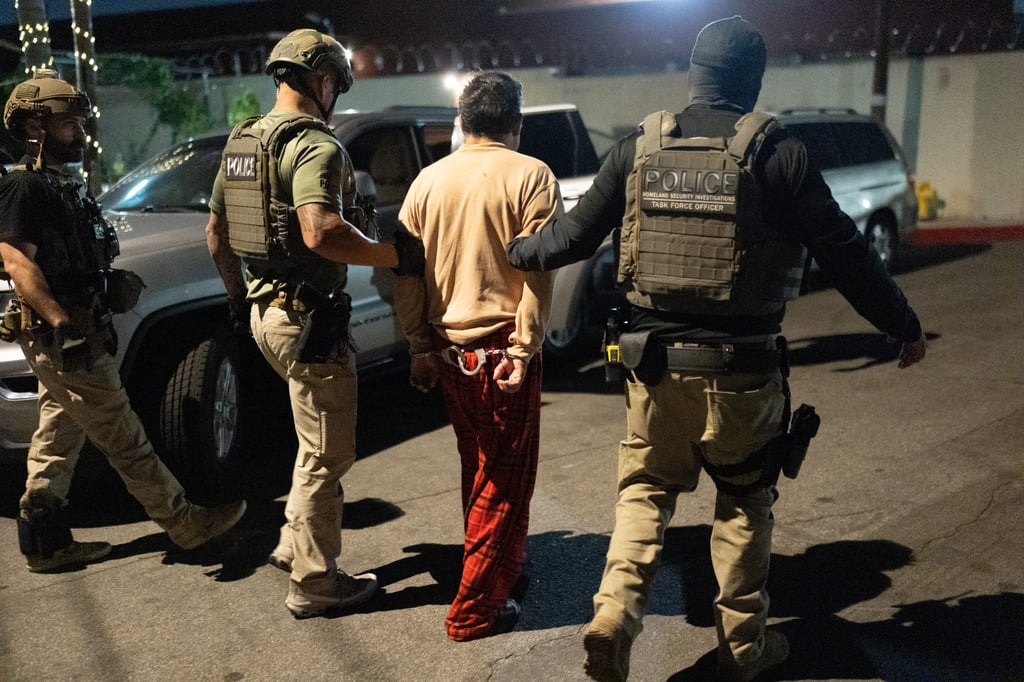 Homeland Security Investigations task force officers escort a suspect accused of illegally registering to vote during a federal operation in Commerce, California on Monday. Photo: AP