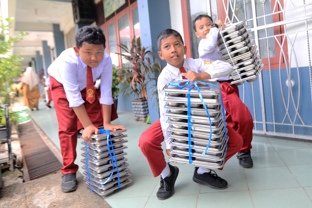 Indonesian students carry free meals at an elementary school in Banda Aceh, Indonesia, in March. Photo: EPA