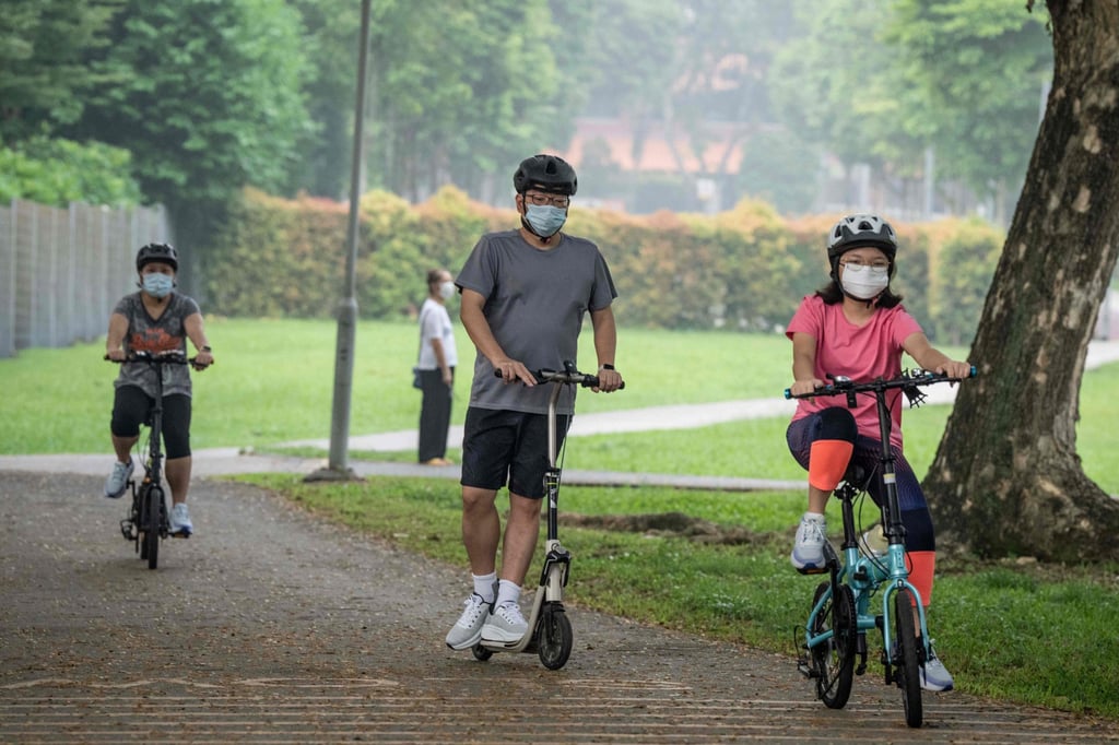 People wearing face masks ride bicycles and scooters through a park in Singapore on Saturday, amid the haze caused by fires in Indonesia. Photo: AFP