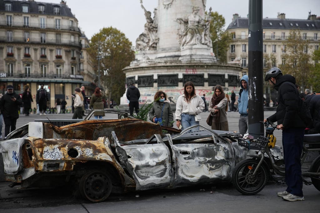 People view a burned-out car in Paris on Tuesday, days after riots erupted across the French capital. Photo: AP