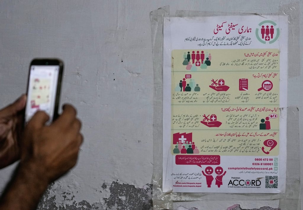 A man takes a photo of a poster with safety resources for factory workers at a Pakistan Institute of Labour Education & Research office in Karachi on October 3. Photo: AP
