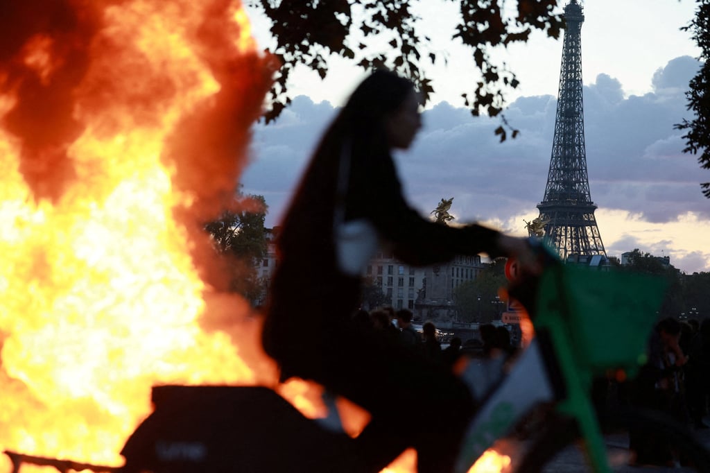 A woman rides a bicycle past a burning barricade near the Tuileries Garden in Paris on Saturday. Photo: Reuters