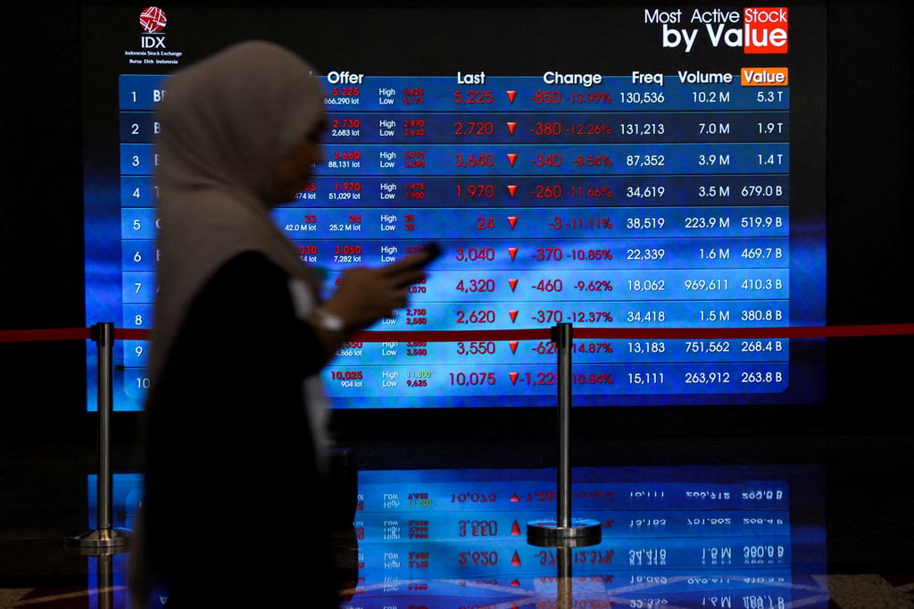 A worker walks past a stock ticker at the Indonesia Stock Exchange in Jakarta, on Friday. Photo: Reuters