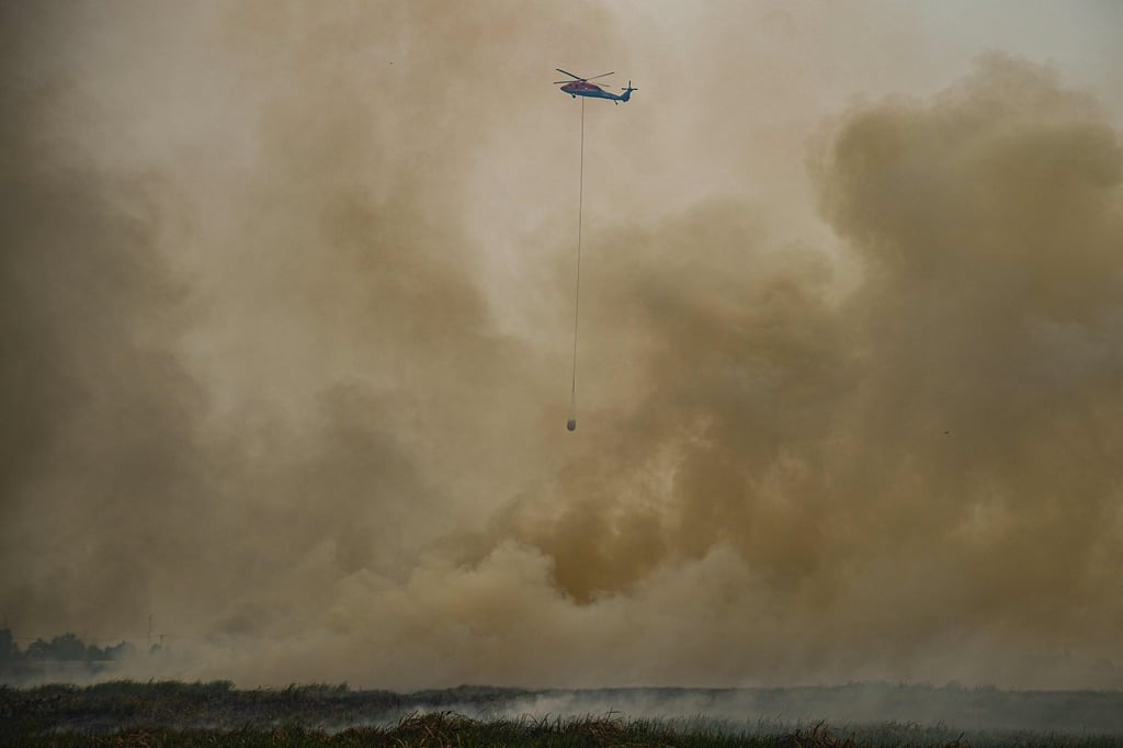 A water-bombing helicopter hovers above heavy smoke in South Sumatra, Indonesia, in September, as forest fire haze severely disrupts aerial firefighting and flights. Photo: AFP