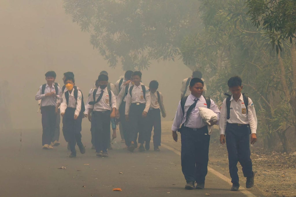 Schoolchildren walk along a smoke-shrouded road in Tegal Arum, Banjarbaru, South Kalimantan, Indonesia, on Monday. Photo: AFP