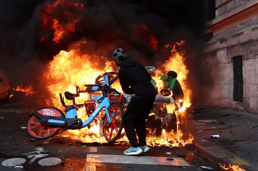A protester throws a bicycle onto a burning car in Paris on October 17. Photo: Reuters