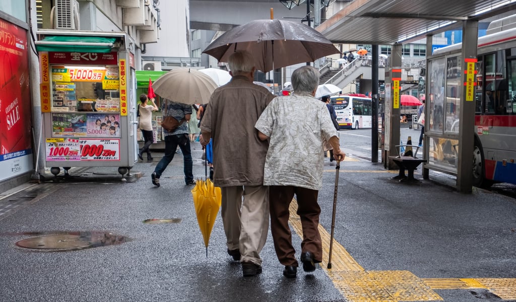 An elderly Japanese couple walks past a bus stop in Tokyo in July 2018. Photo: Shutterstock