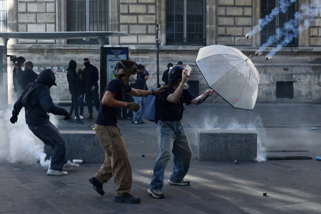 Demonstrators use an umbrella to shield themselves from incoming tear smoke canisters. Photo: Reuters